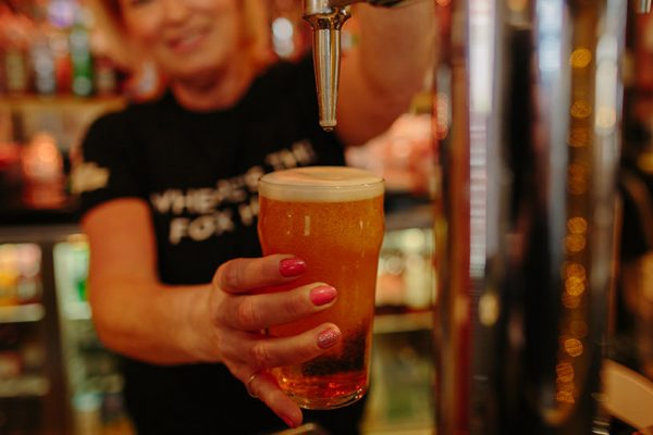woman pulling a pint of ale from a tap