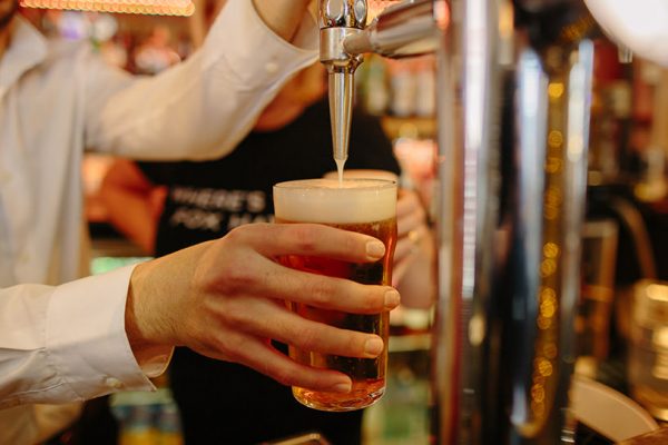 man pouring a pint of beer on tap in a pub