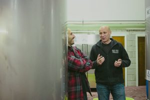 two men chat inside a brewery