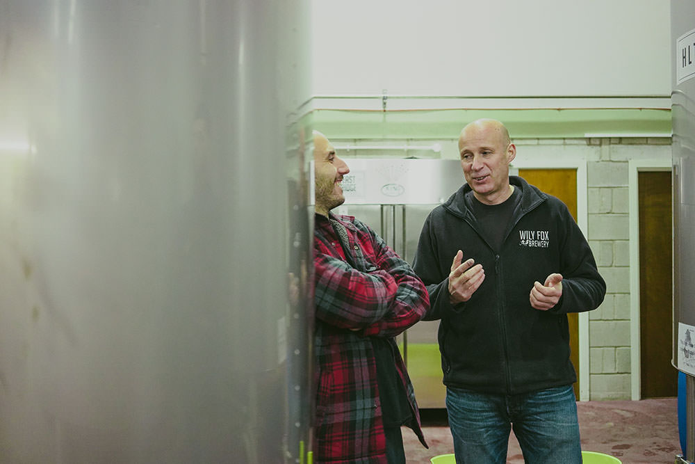two men chat inside a brewery